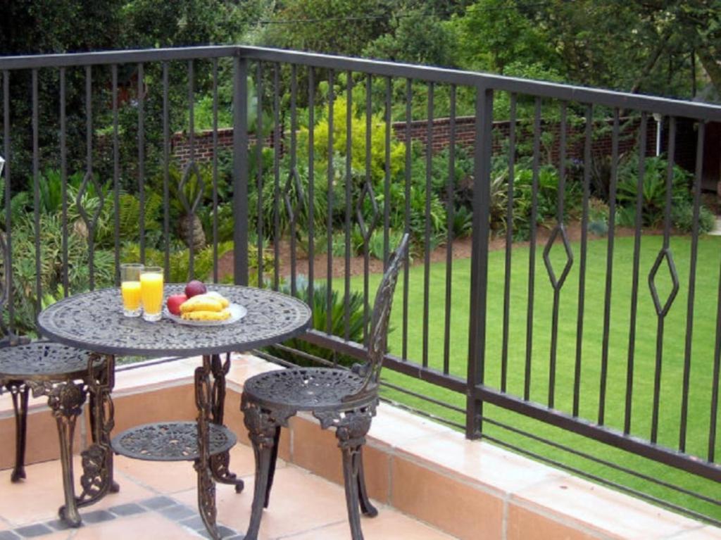 a table with fruit and drinks on a balcony at Gallo Manor Executive Bed & Breakfast in Johannesburg