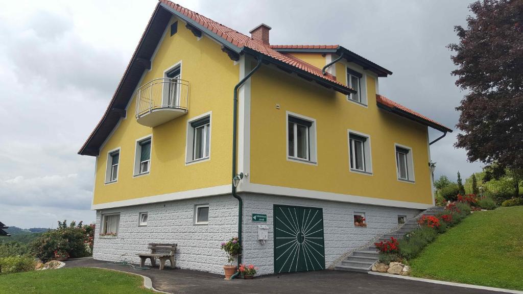 ein gelbes und weißes Haus mit einer Bank davor in der Unterkunft Gästehaus Jeindl in Hartmannsdorf