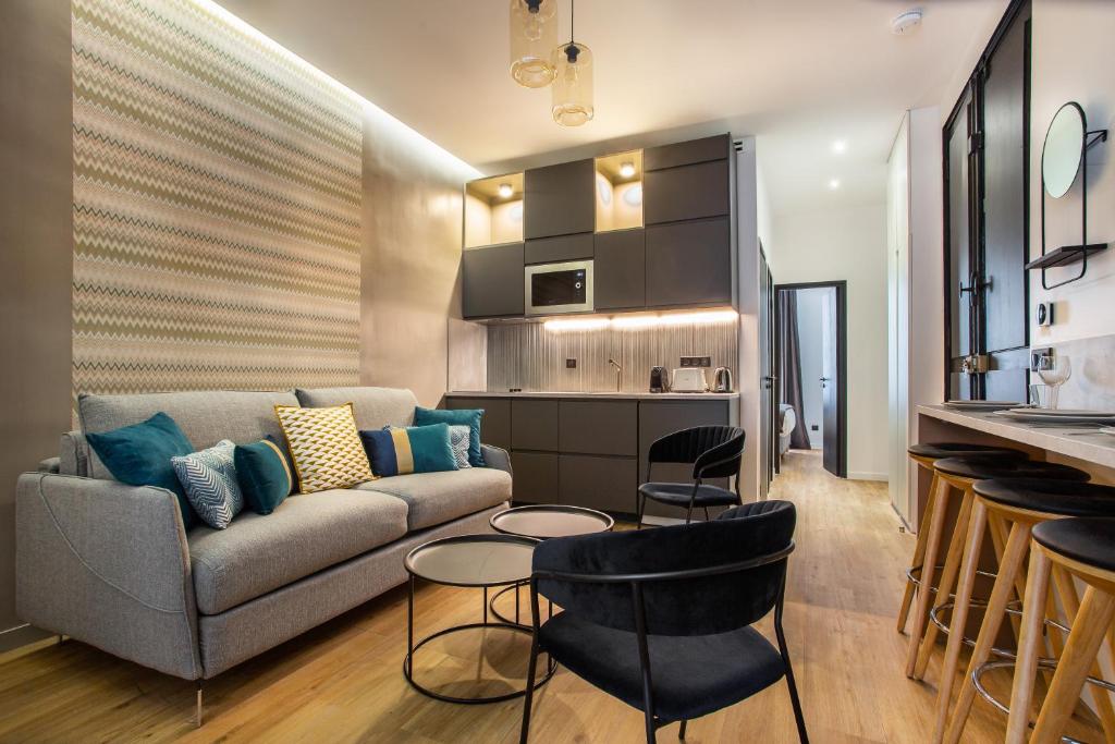 un salon avec un canapé et des chaises et une cuisine dans l'établissement CMG - Grand Boulevard - Poissonière, à Paris