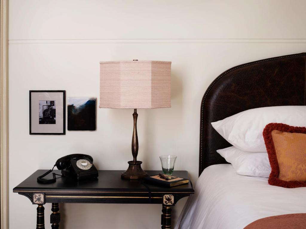 ein Bett mit einem Tisch mit einer Lampe und einem Telefon in der Unterkunft NoMad London in London