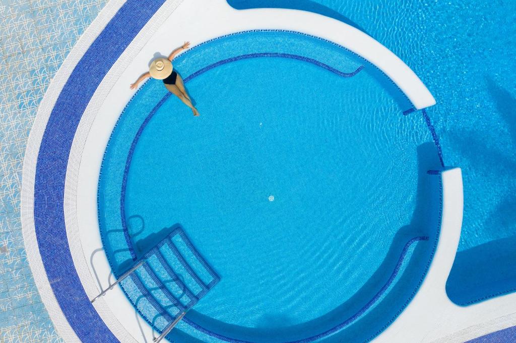 a man is swimming in a swimming pool at MUR Faro Jandia Fuerteventura & Spa in Morro del Jable