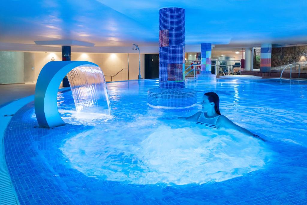 a woman swimming in a pool with a water fountain at MUR Faro Jandia Fuerteventura & Spa in Morro del Jable