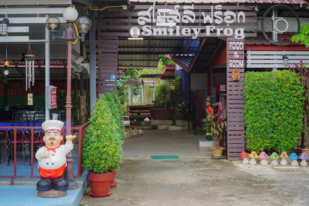 een standbeeld van een kerstman voor een gebouw bij Smiley frog in Kanchanaburi