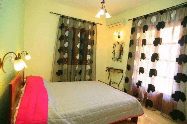 a bedroom with a bed and a window with curtains at Emily's Apartments in Kassiopi