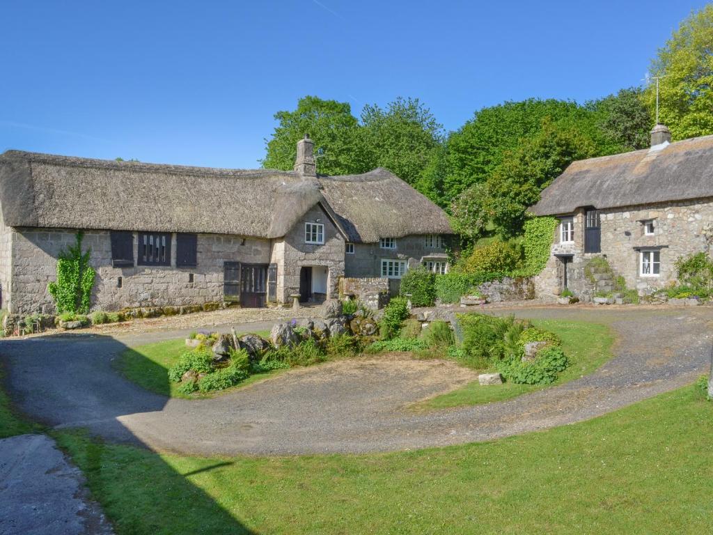 an old stone house with a thatched roof at Hole Farm in Gidleigh
