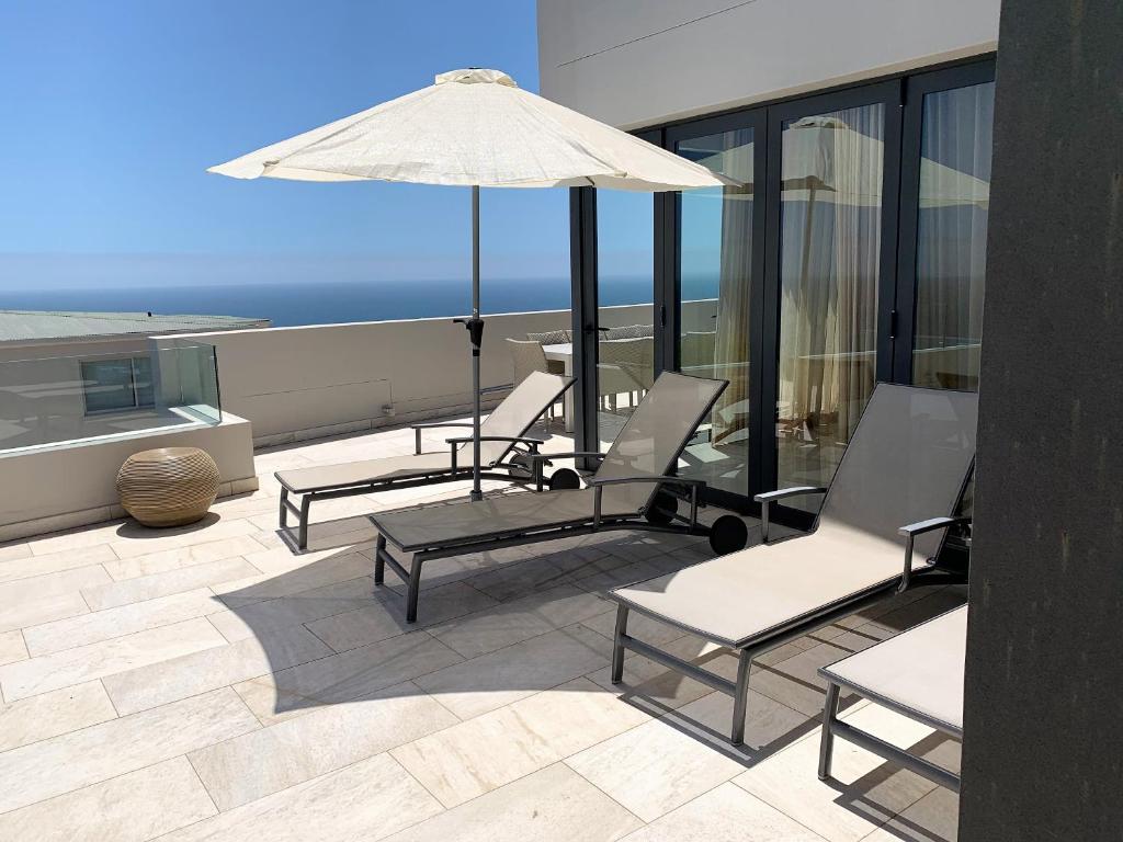 a group of chairs and an umbrella on a patio at 6 on Clifton - Spacious 2 bedroom apartment in Cape Town