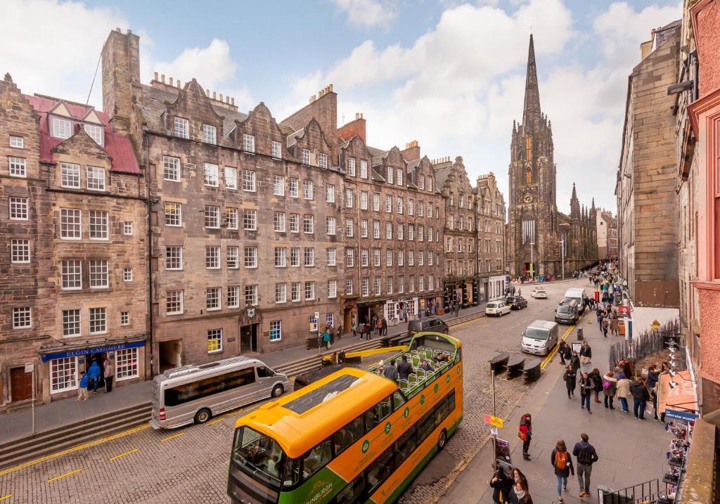 un autobús amarillo conduciendo por una calle de la ciudad con edificios en Ladystairs 1 Royal Mile, en Edimburgo