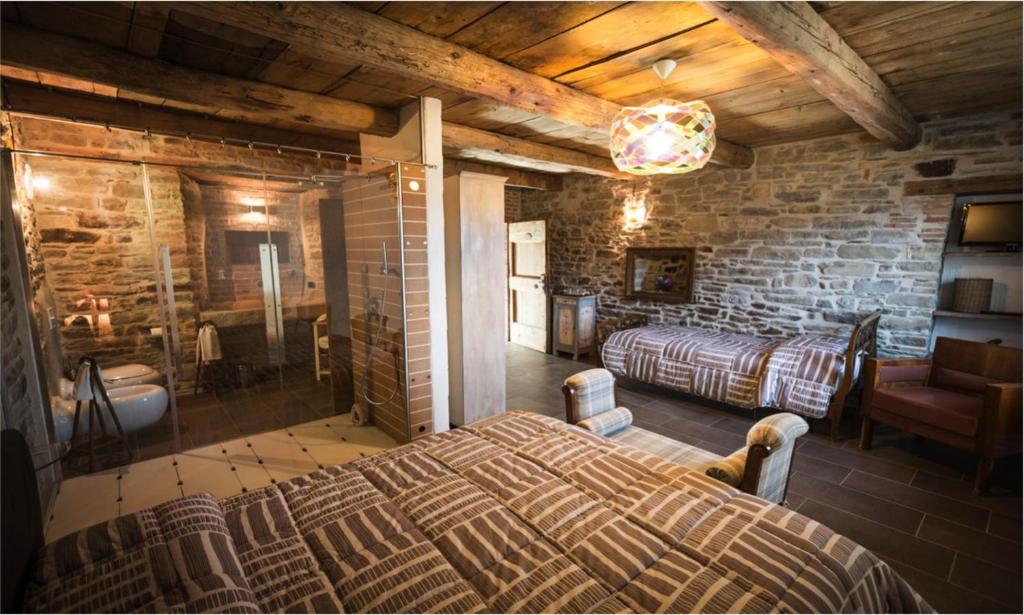 - une chambre avec un grand lit dans un mur en briques dans l'établissement La Locanda Della Campanara, à Santa Sofia