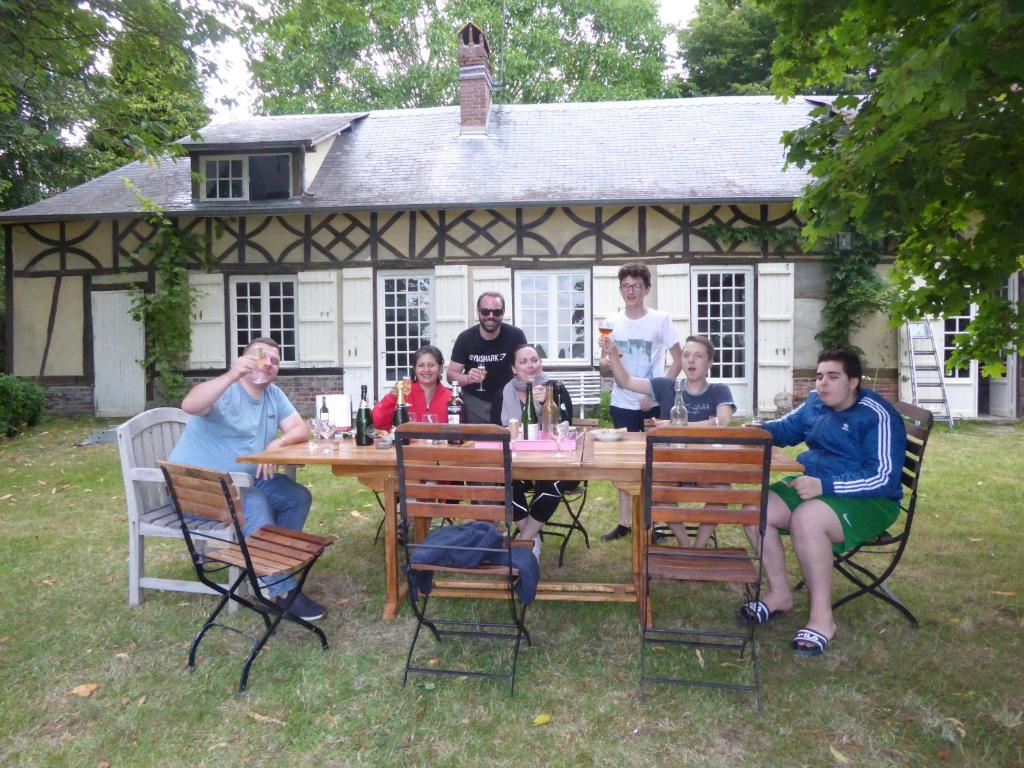 a group of people sitting at a table in front of a house at Orfea s home - maison de charme, Lyons-la-Forêt, accès direct forêt in Le Tronquay