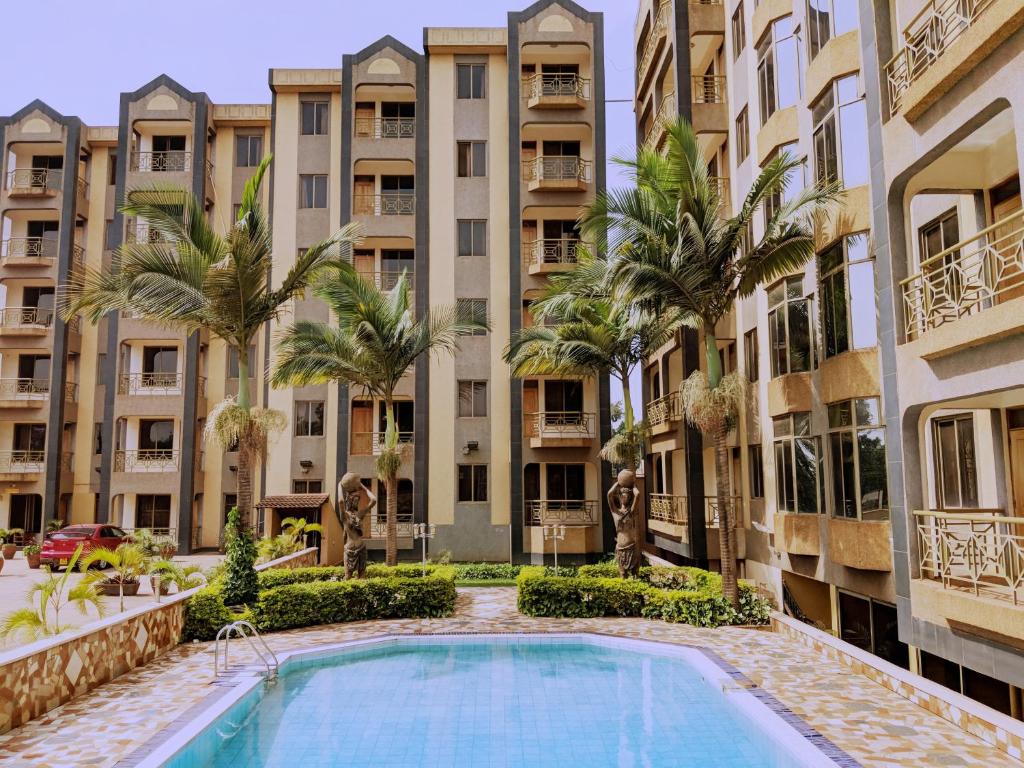 an apartment complex with a swimming pool and palm trees at Prestige Hotel Suites in Kampala