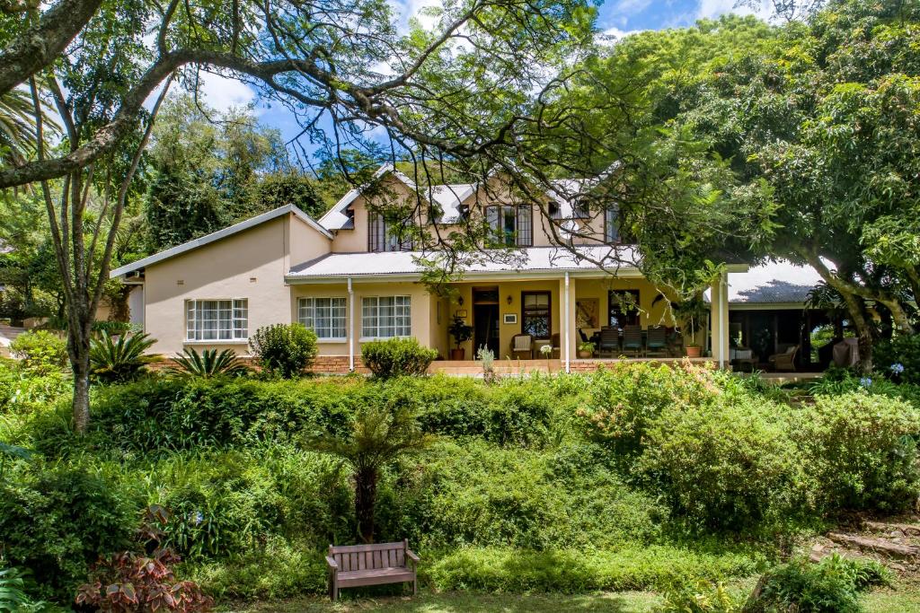 ein weißes Haus mit einer Bank im Hof in der Unterkunft Porcupine Ridge Guest House in Sabie