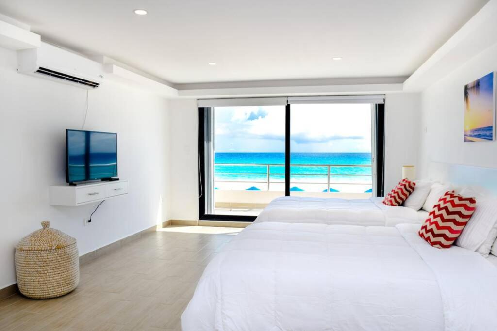 a white bedroom with a view of the ocean at Villas Marlin 108, a pie de playa, albercas, jacuzi, ubicacion inmejorable in Cancún