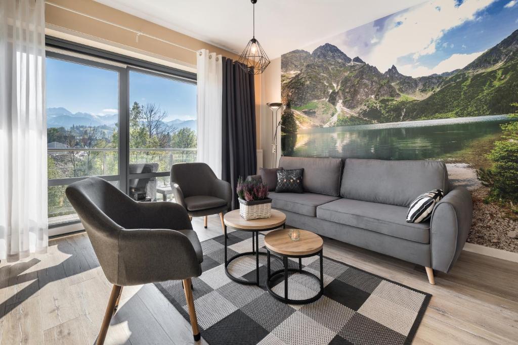 a living room with a couch and chairs and a large window at VIP Apartamenty Szklane Domy The View in Zakopane