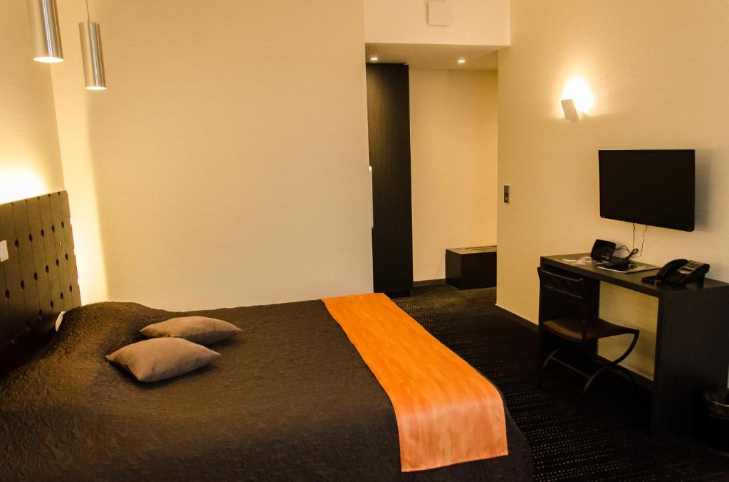ベテューヌにあるル ヴュー ベフロワのベッド、デスク、テレビが備わるホテルルームです。
