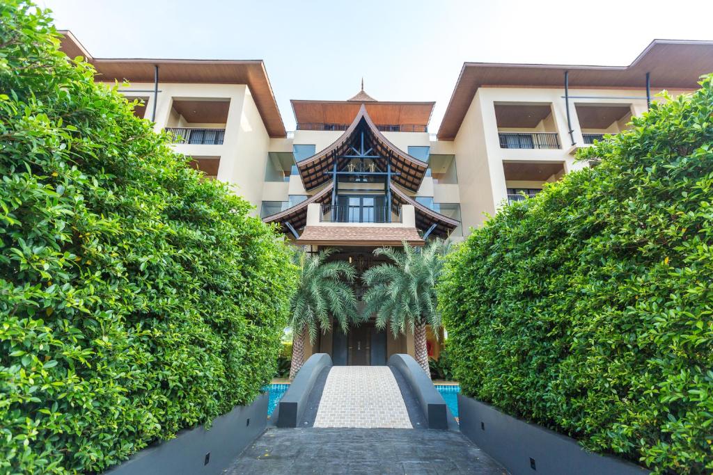 a view of a building from between two hedges at Aurico Kata Resort & Spa - SHA Extra Plus in Kata Beach