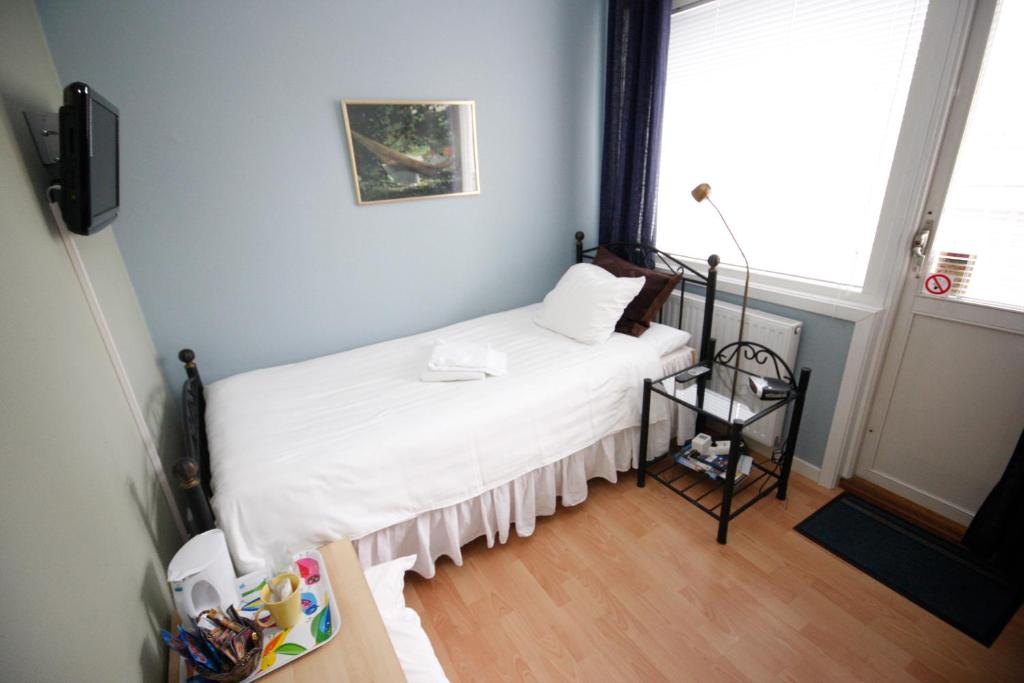 1 dormitorio con 1 cama con sábanas blancas y ventana en Hotell Zlafen Bed and Breakfast, en Karlskoga