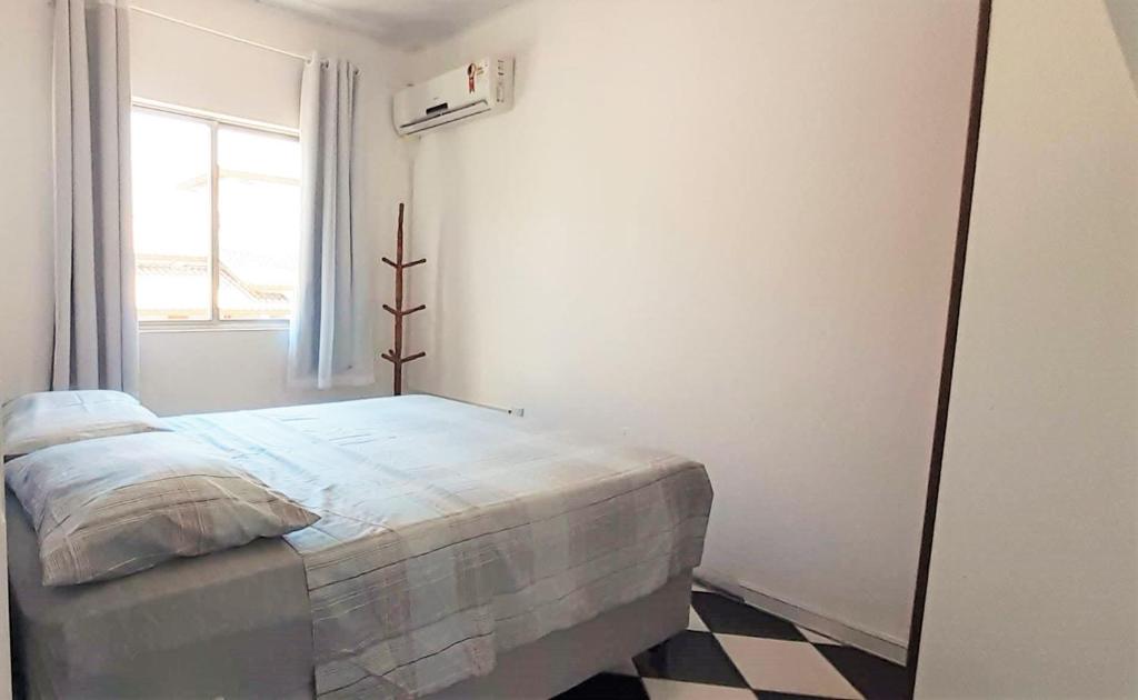 a white bedroom with a bed and a window at Residencial di Raffaele em Bombinhas in Bombinhas
