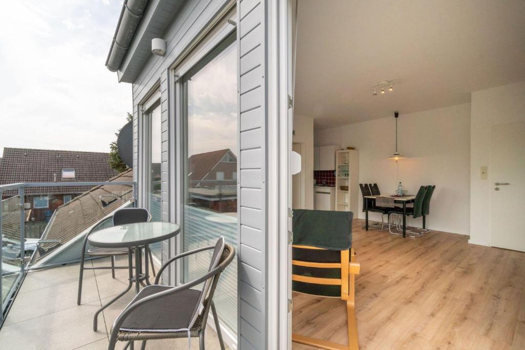 a room with a balcony with a table and chairs at Ferienhaus-Butenboerkumer in Borkum