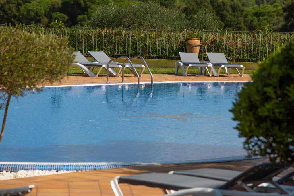 a row of lounge chairs next to a swimming pool at RVHotels Golf Costa Brava in Santa Cristina d'Aro