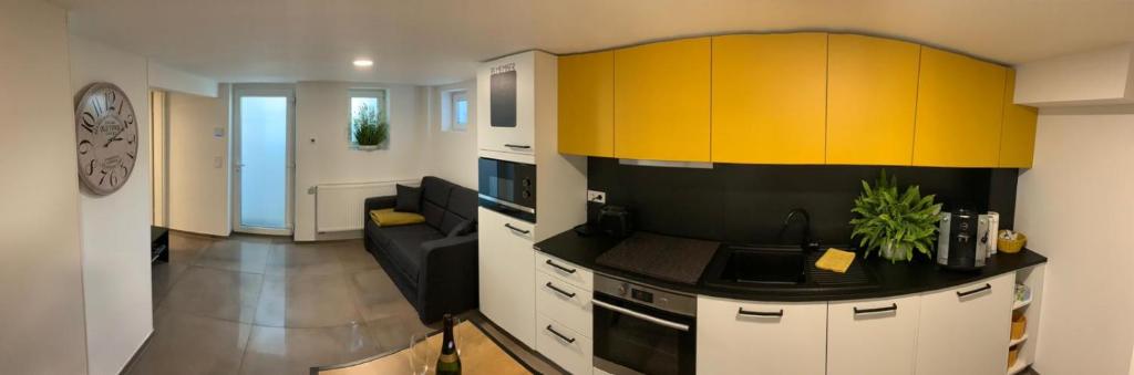 a kitchen with yellow and black cabinets and a living room at Joanna Apartment - MA Casterfeld in Mannheim
