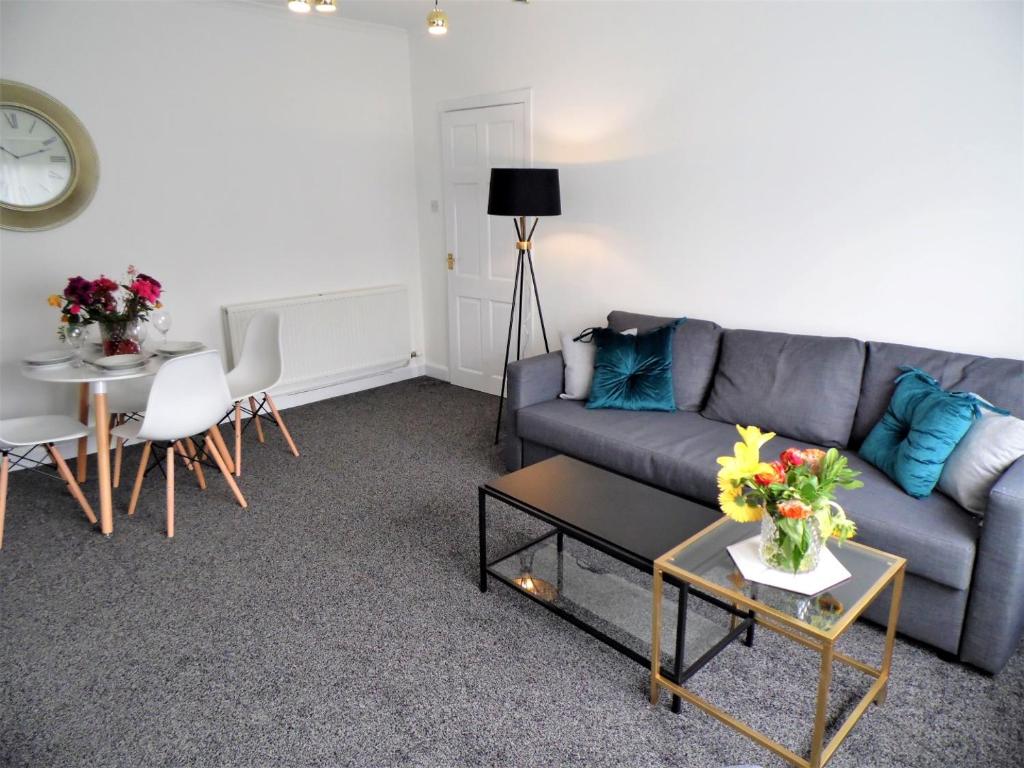 una sala de estar con un sofá y una mesa en Penilee Upper Apartment, en Glasgow