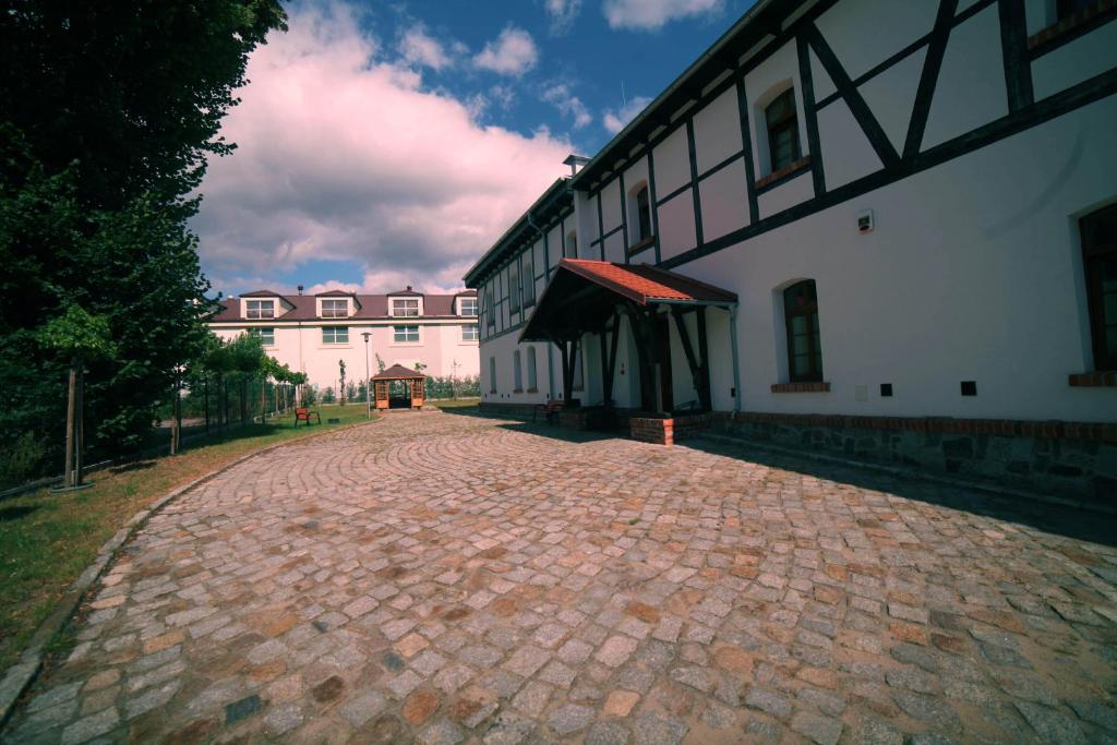 uma estrada de tijolos ao lado de um edifício branco em Noclegi Stara Wozownia em Piła