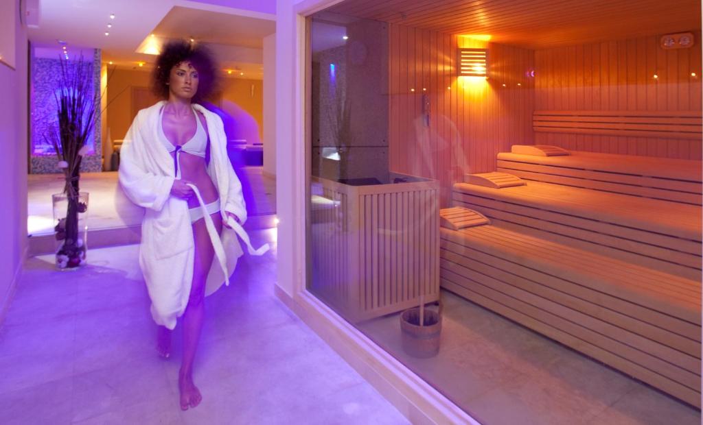 una donna che cammina in una stanza con sauna di Vittoria Resort Pool & SPA a Otranto
