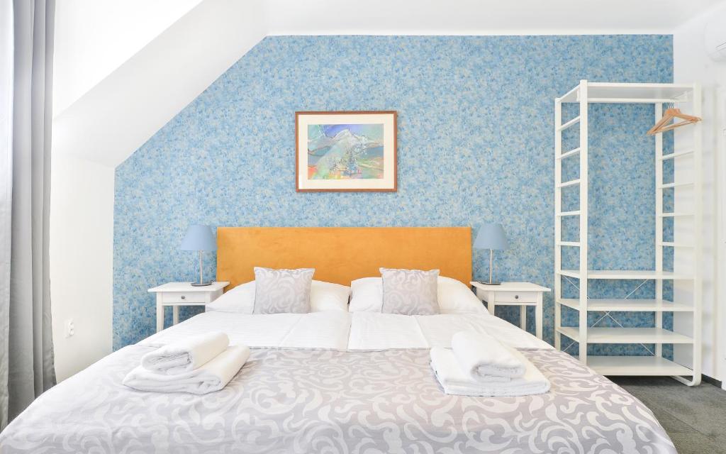 ein Schlafzimmer mit einem Bett und einer blauen Wand in der Unterkunft BlueBell Hotel in Bratislava