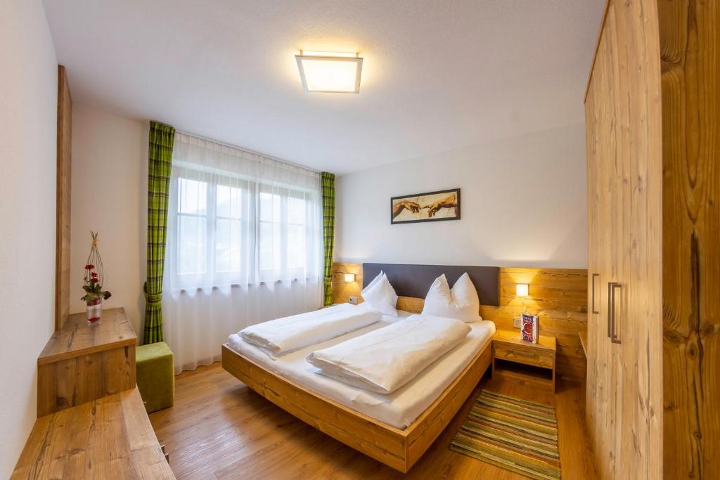 ein Schlafzimmer mit einem großen Bett und einem Fenster in der Unterkunft Hotel Garni Angerer in Luttach