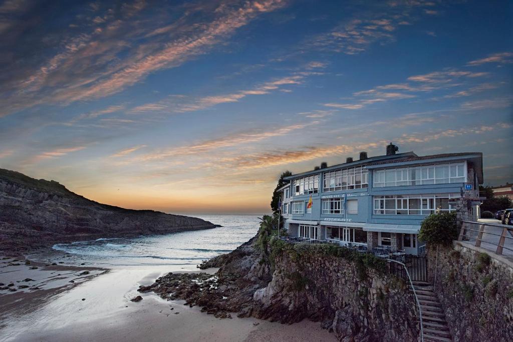 a building on a cliff next to the ocean at Hotel Sablón in Llanes
