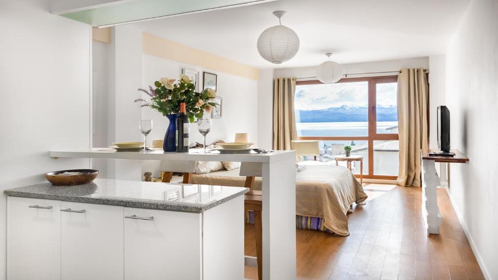 cocina blanca con cama y mesa con copas de vino en Tu Apart en Bariloche 4 en San Carlos de Bariloche