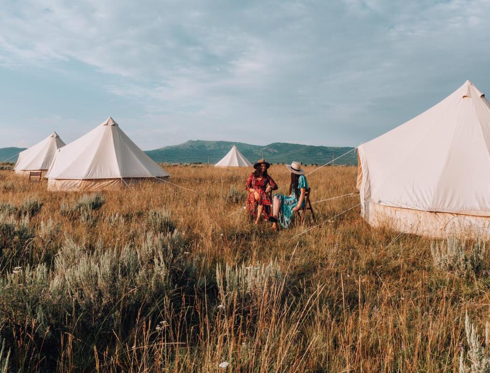 dos personas parados frente a tiendas en un campo en Wander Camp Yellowstone en Island Park