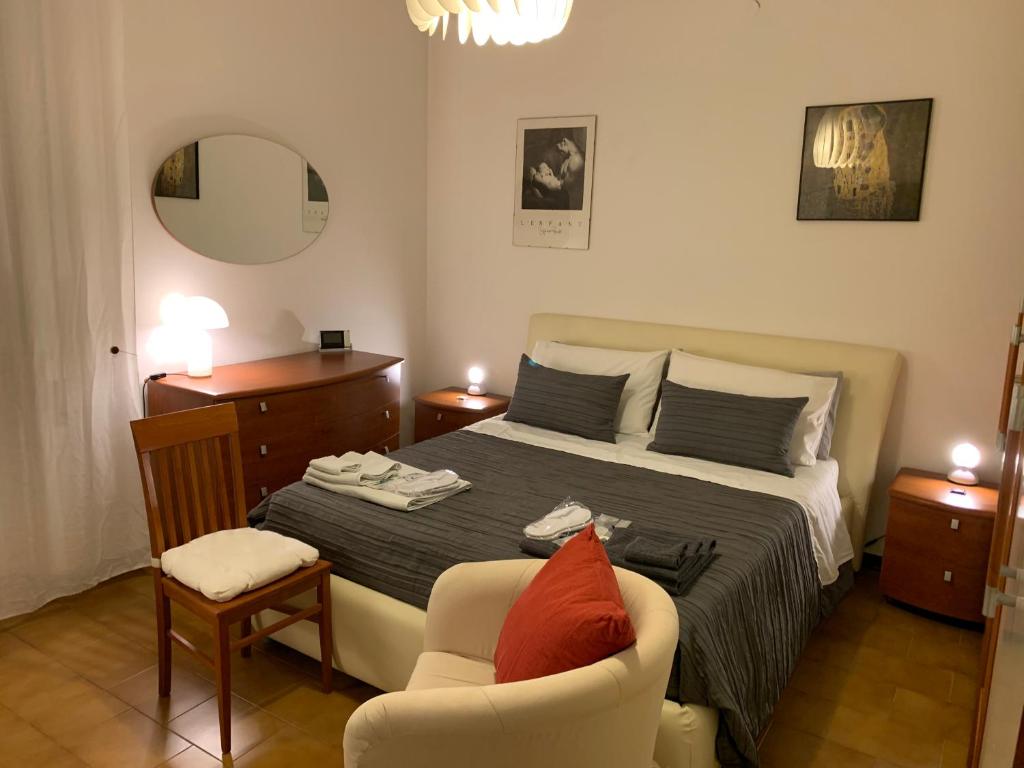 a bedroom with a bed and a chair and a mirror at Pampero & Catona House in Pisa