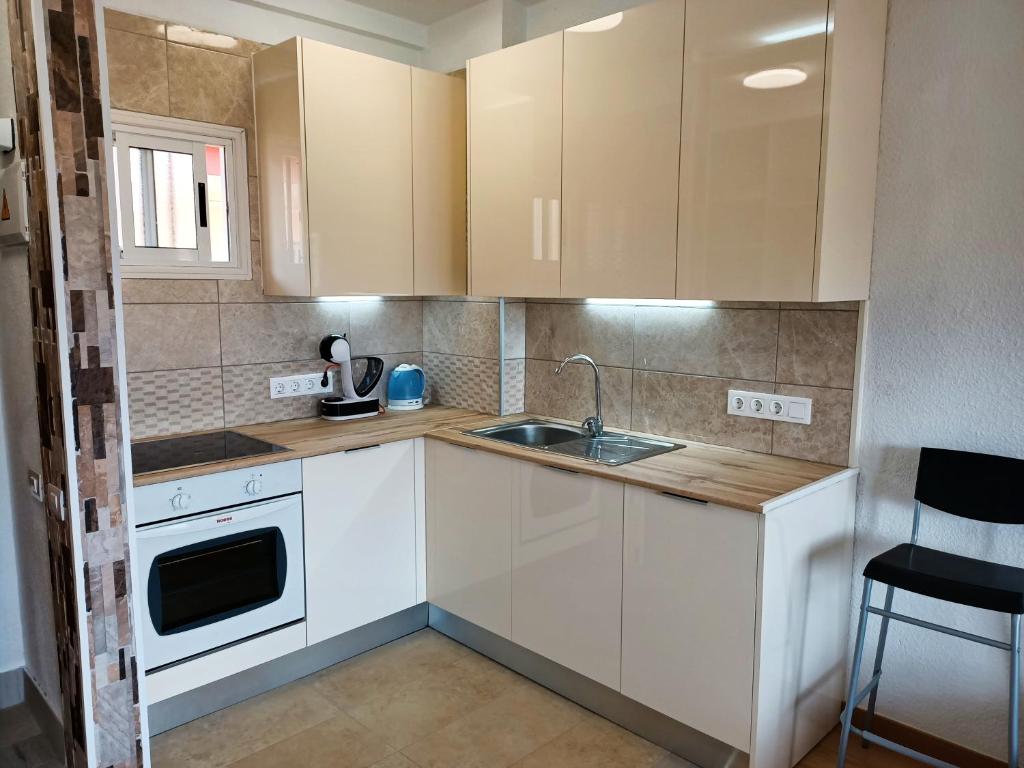a small kitchen with white cabinets and a sink at Sea view 1B Los Cristianos in El Guincho