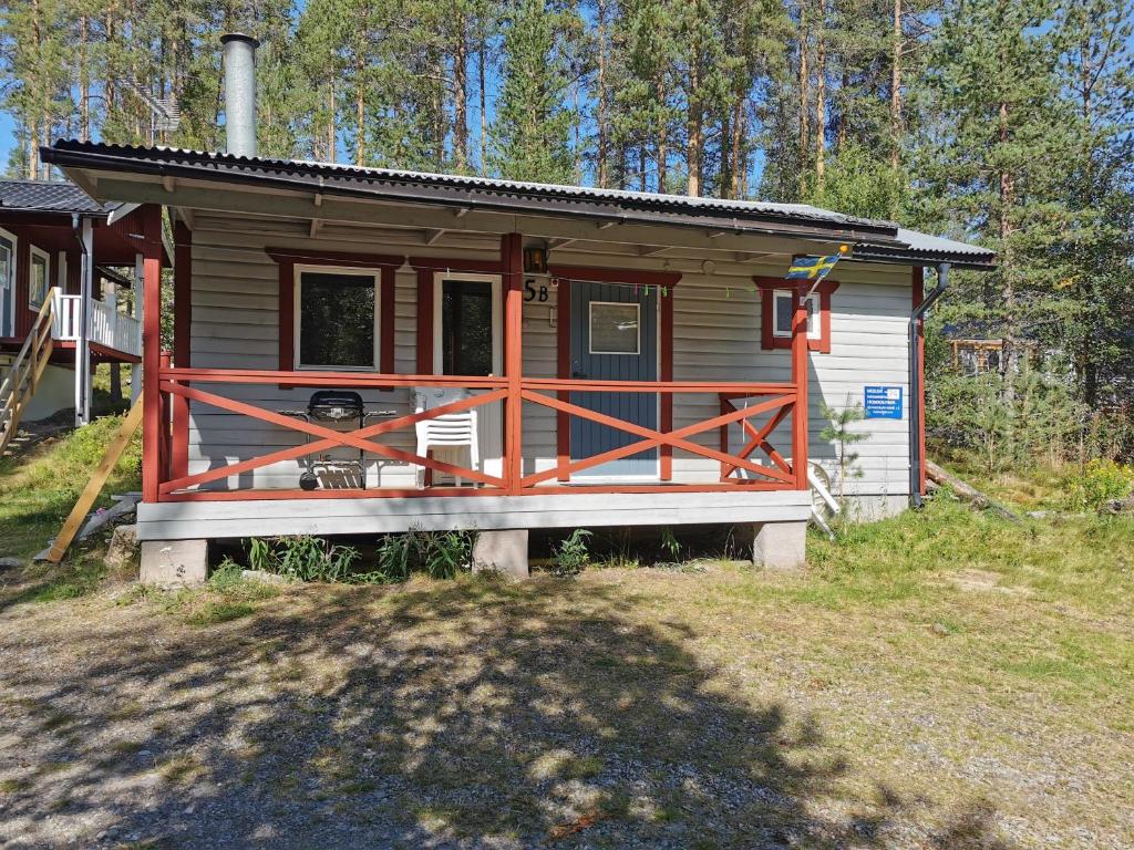 a small cabin with a wooden porch in the woods at Fjällstuga 5B i Foskros m kamin in Idre