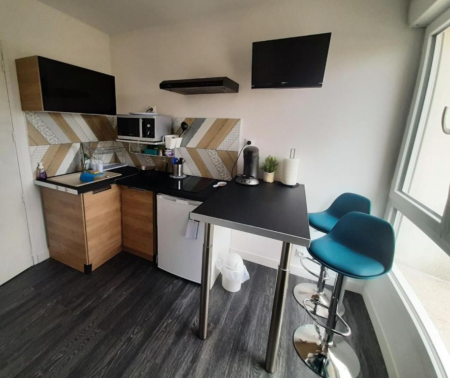 a small kitchen with a table and two blue chairs at Studette accès plage in Saint-Jean-de-Monts