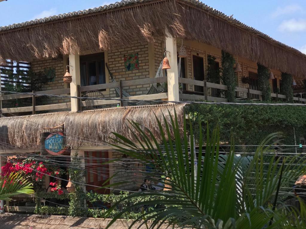 a building with a thatched roof and plants at Pousada Mar e Sol in Pipa