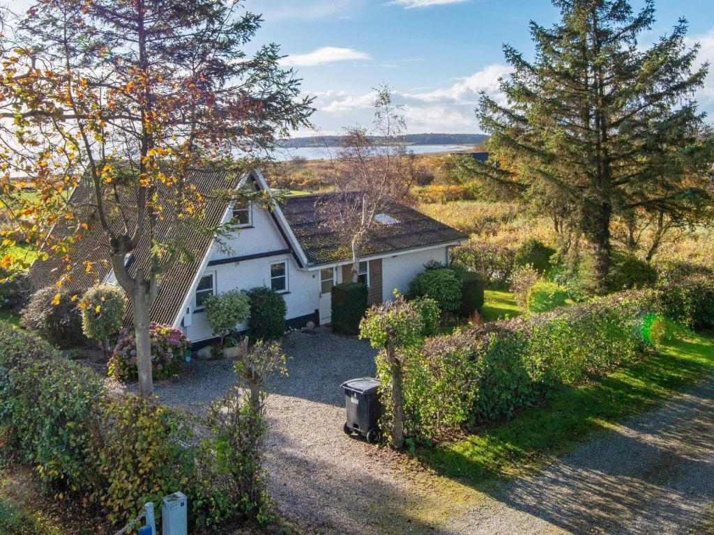 Årøsundにある6 person holiday home in Haderslevの木々の茂る庭の小さな白い家