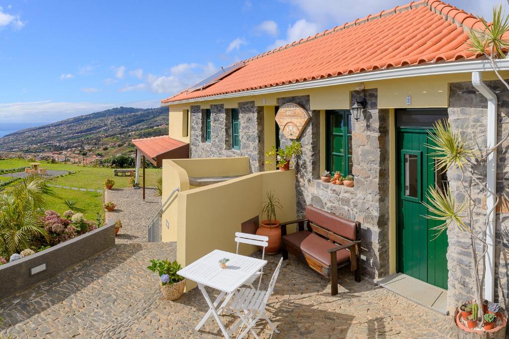 una casa con una puerta verde y una mesa en Recanto das Florenças (2) en Arco da Calheta