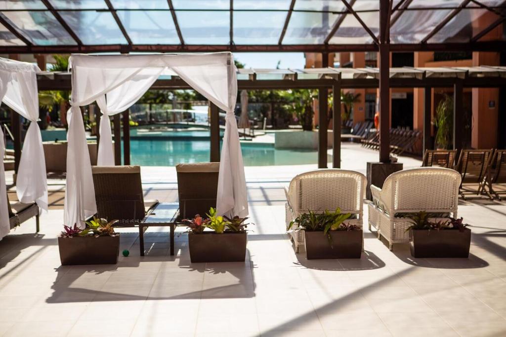 um pátio com cadeiras, uma tenda e uma piscina em Studio à beira mar - Hotel Jurerê Beach Village em Florianópolis