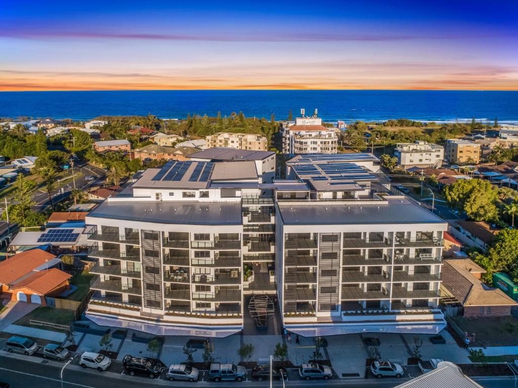 an aerial view of a building with the ocean in the background at Hedge Apartments by CLLIX in Buddina