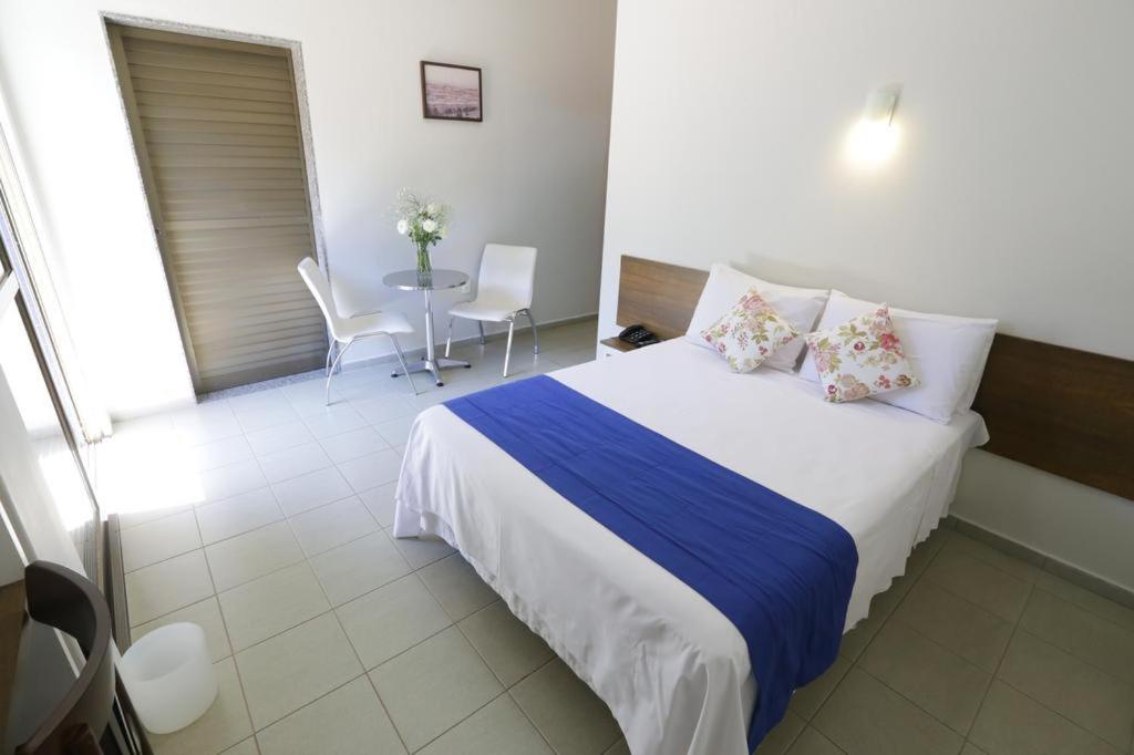 a bedroom with a bed and a table with chairs at Hotel Porto do Sol in Caetité