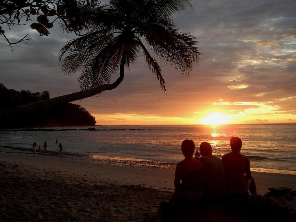 雅各的住宿－Punta Leona Beach Condos，一群坐在海滩上的人,看着日落
