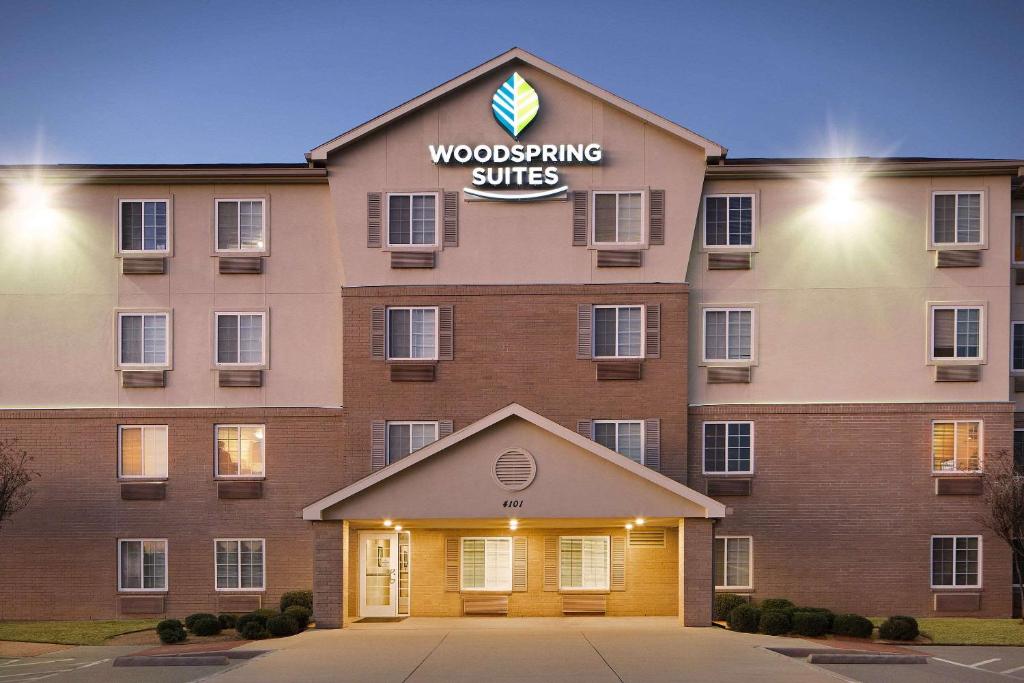 un bâtiment avec un panneau indiquant des suites en bois dans l'établissement WoodSpring Suites Fort Worth Forest Hill, à Forest Hill