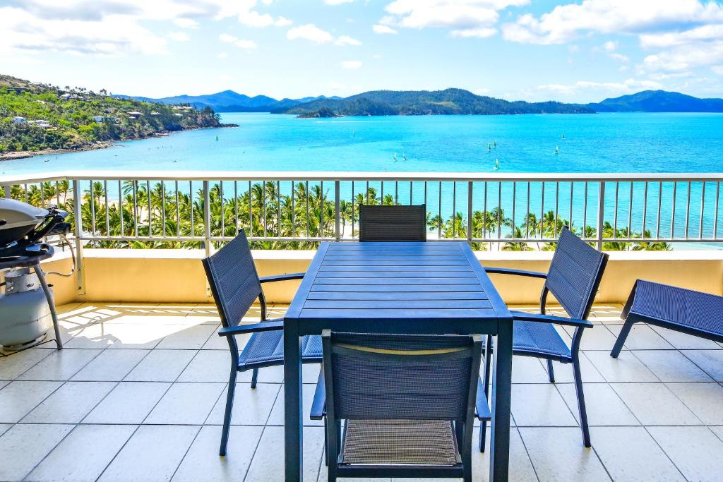 una mesa y sillas en un balcón con vistas al océano en Whitsunday Apartments on Hamilton Island by HIHA, en Hamilton Island