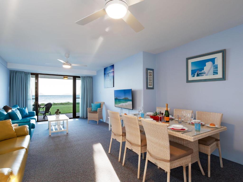 a living room with a dining room table and a couch at Harbourside 4 ground floor on the waterfront in Soldiers Point