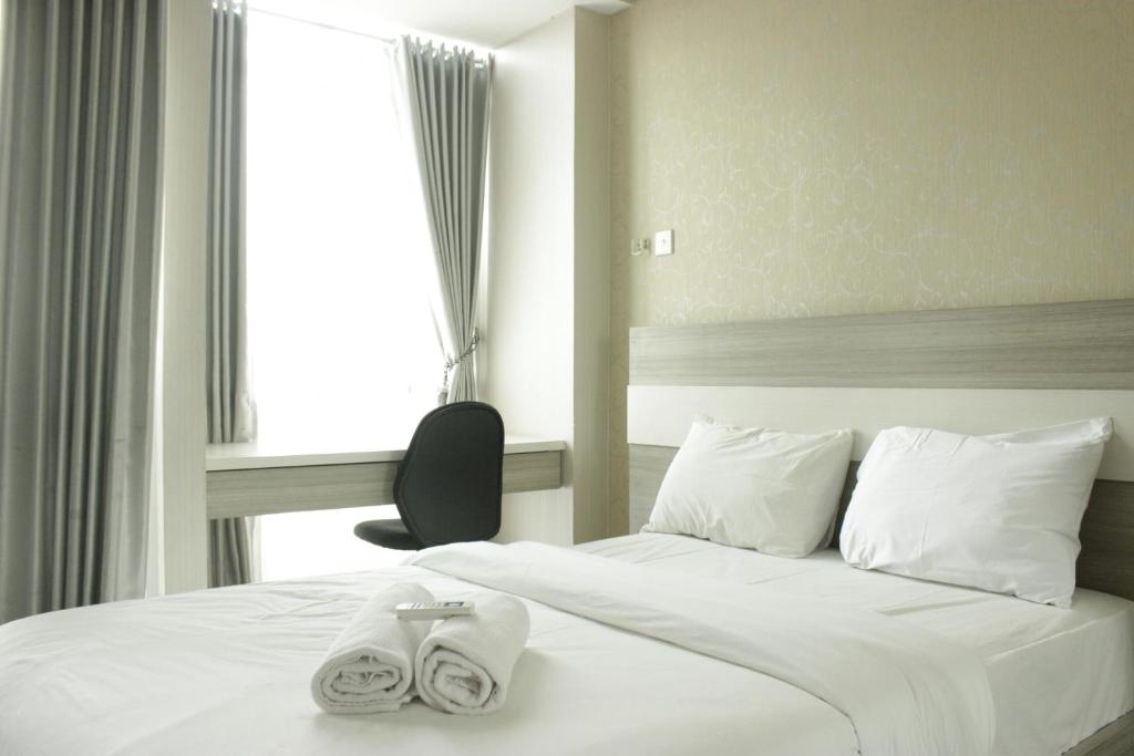 JatirokeComfy Studio Apartment near UNPAD Taman Melati Jatinangor By Travelio的酒店房间里有一张床，上面放着毛巾