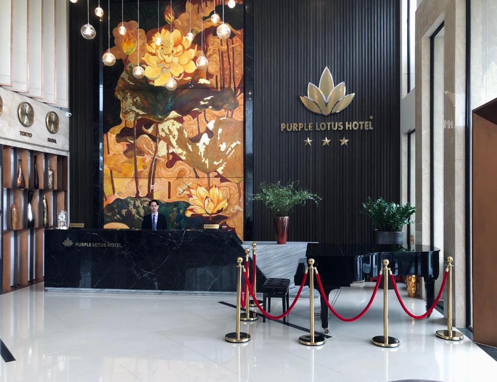 a man in a suit standing at a podium in a lobby at Purple Lotus Hotel in Hải Dương