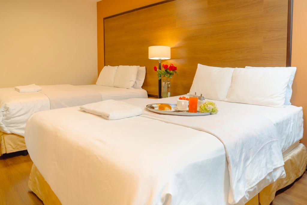 Dos camas en una habitación de hotel con un plato de comida en Hotel La Farola, en Cuenca