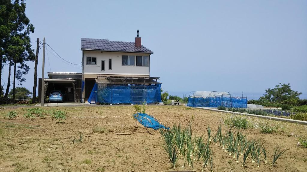 una casa con un pájaro azul sentado en un campo en 日本海 能生の宿 見晴らし亭 en Nō